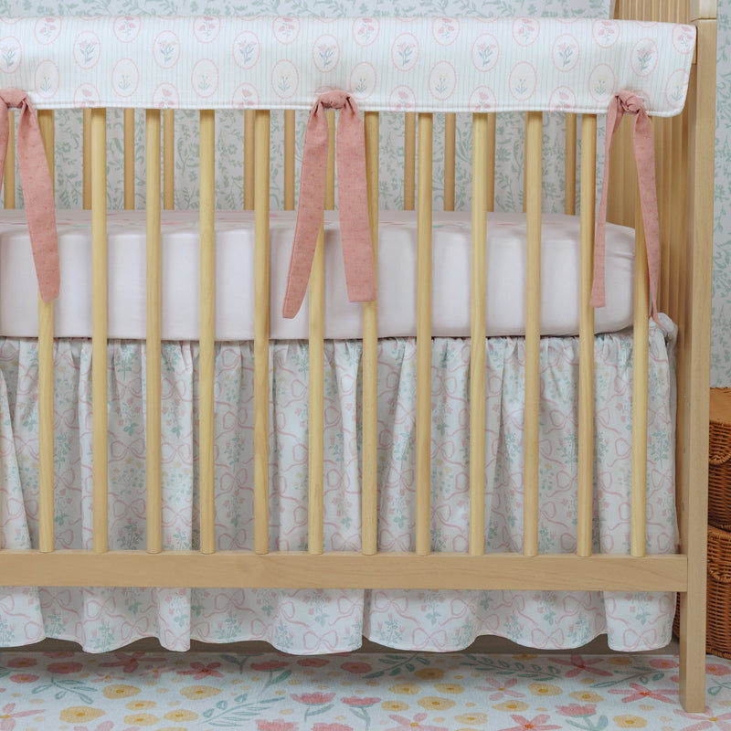 Wooden crib with pink ribbon ties in a nursery setting