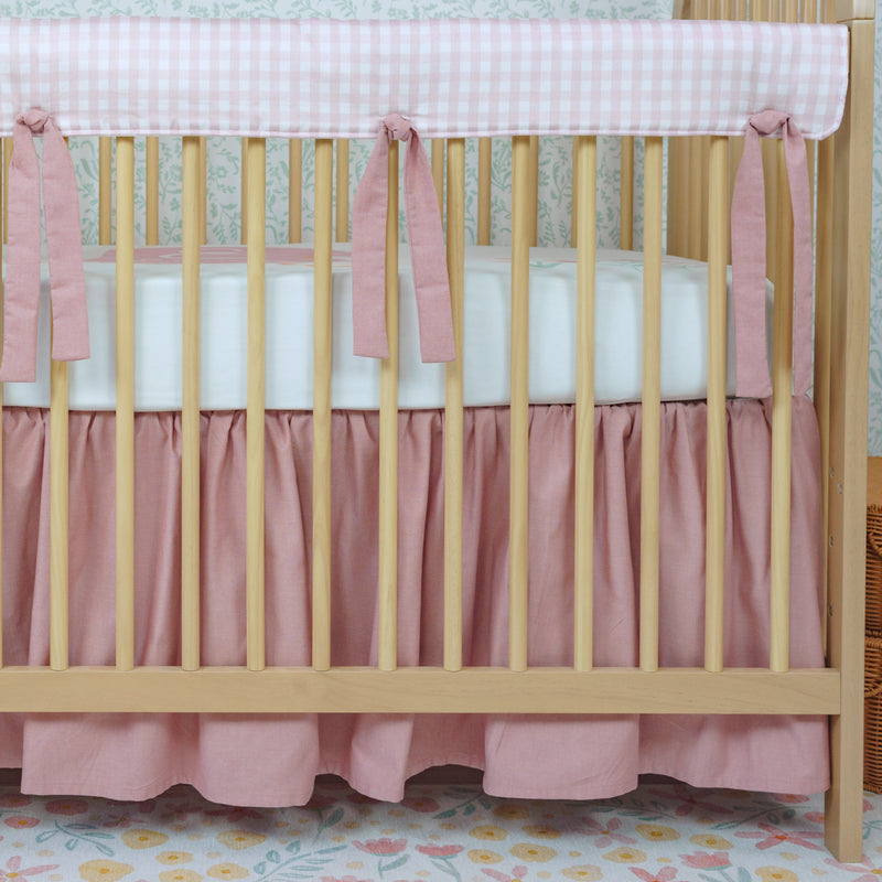 Wooden crib with pink bedding in a nursery setting