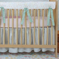 Nursery room with a crib decorated with floral bedding and green ribbons.