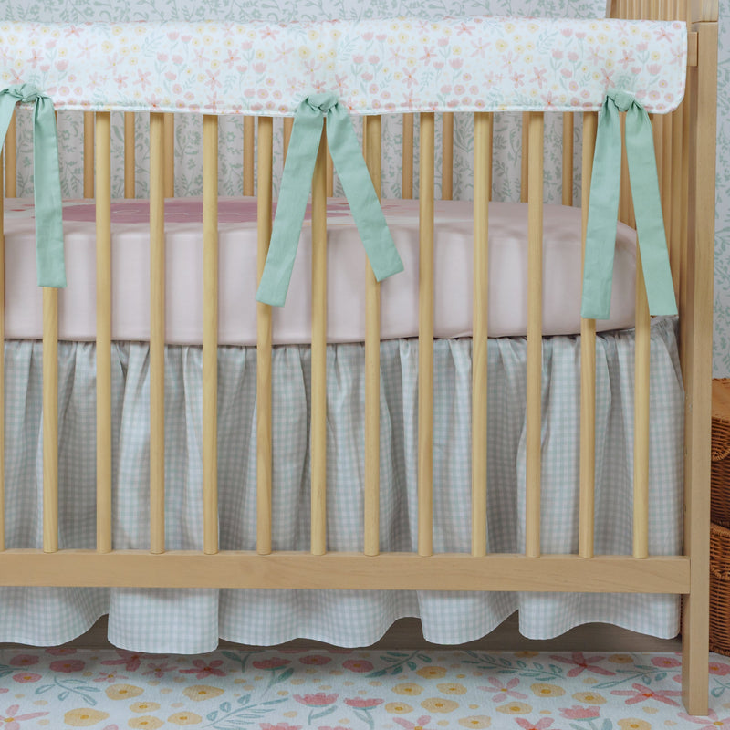 Nursery room with a crib decorated with floral bedding and green ribbons.