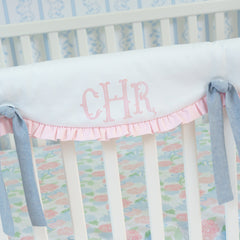 Baby crib with floral bedding and pink ruffles, featuring the name 'CHR' on a white background.