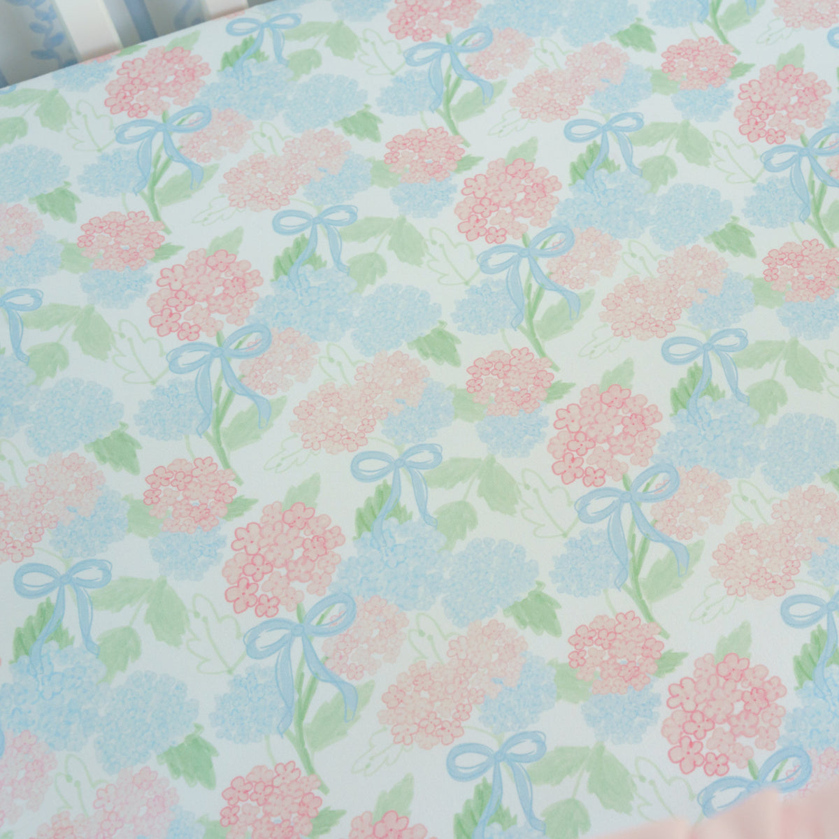 Floral patterned fabric with pink flowers and blue bows on a light blue background.