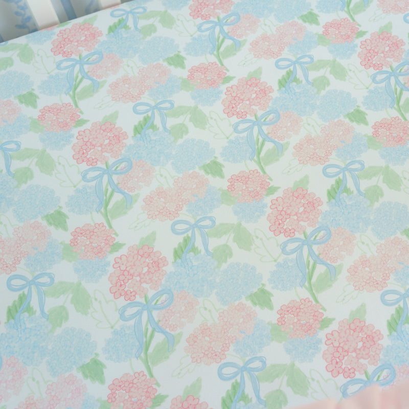 Floral patterned fabric with pink flowers and blue bows on a light blue background.