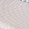 Pink crib sheet with white polka dots and a colorful border