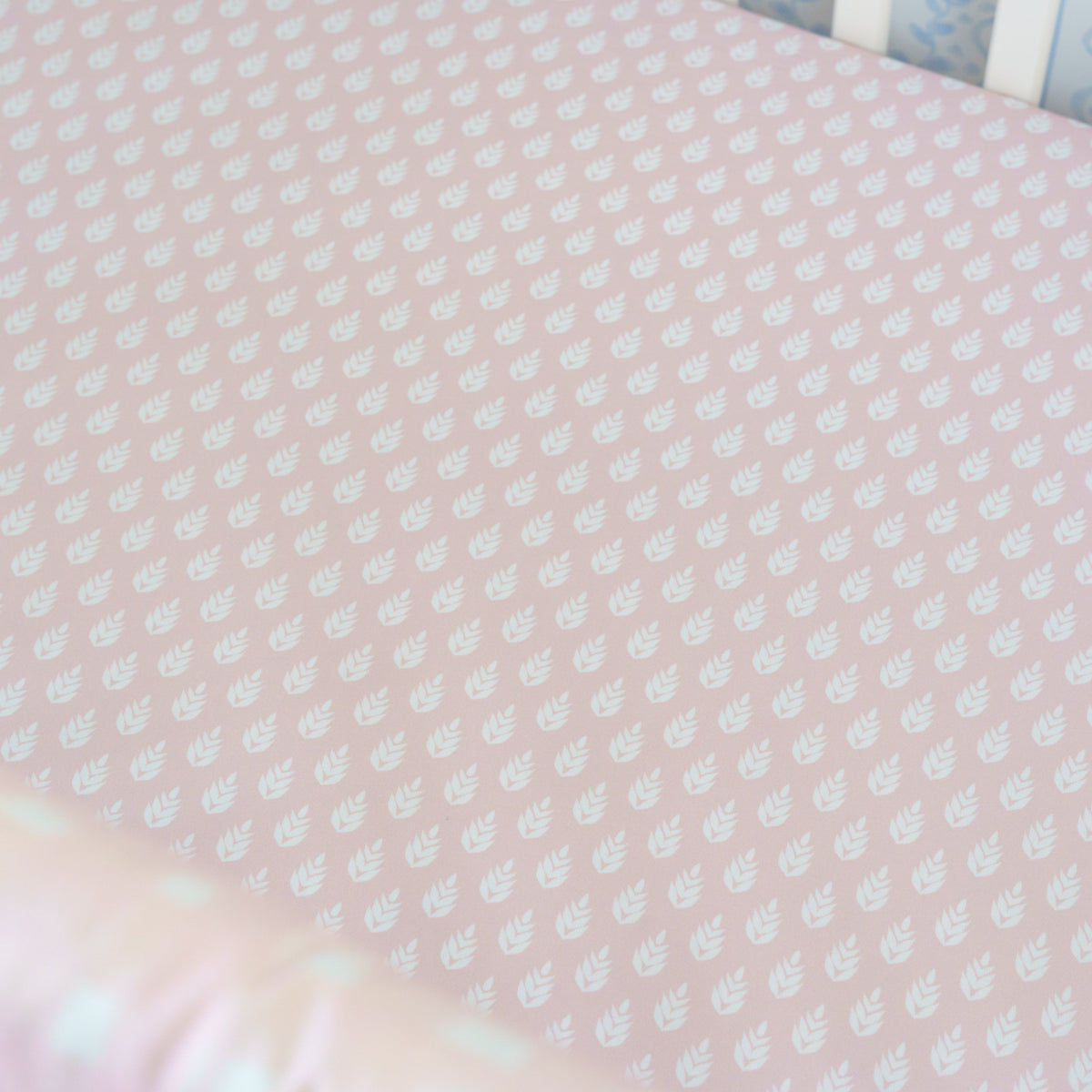 Pink crib sheet with white polka dots and a colorful border