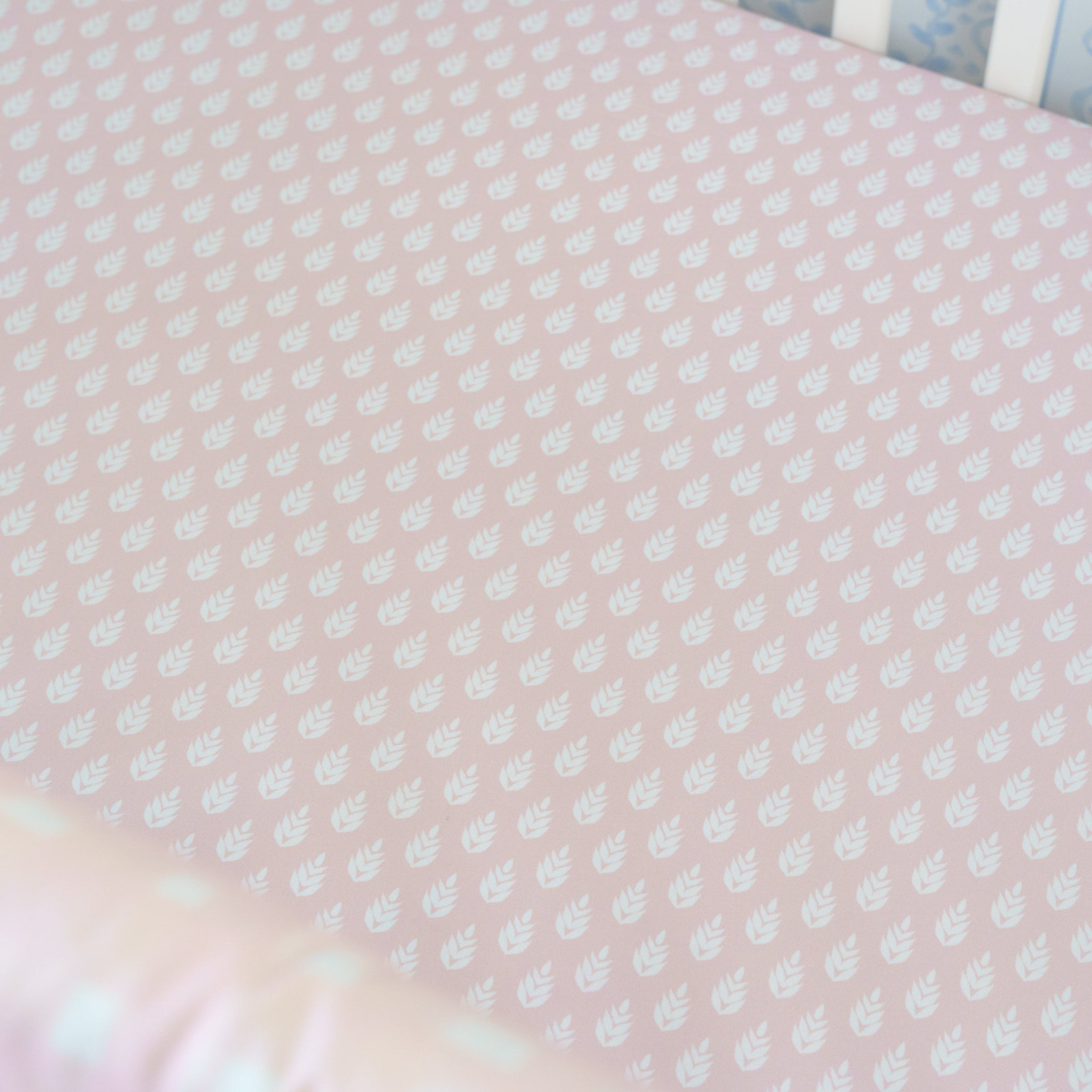 Pink crib sheet with white polka dots and a colorful border