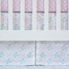 Crib with floral-patterned crib skirt in pink and blue