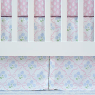 Crib with floral-patterned crib skirt in pink and blue