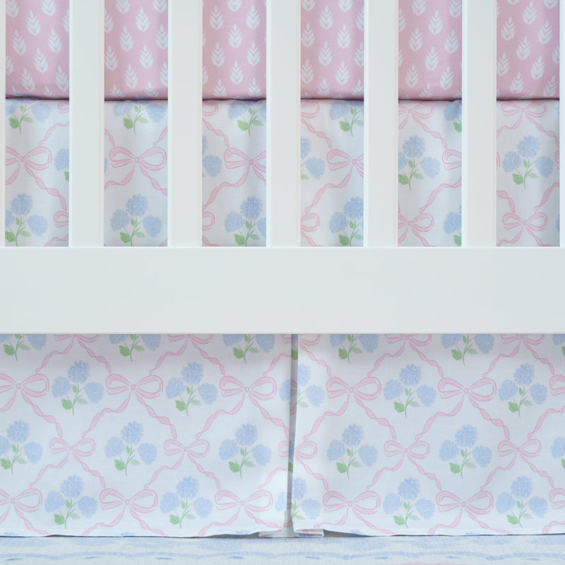 Crib with floral-patterned crib skirt in pink and blue