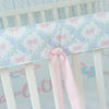 Crib rail cover with floral pattern and pink bow on a white crib