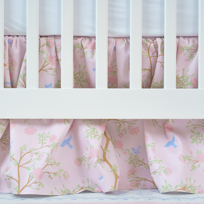 Crib with pink floral crib skirt and white crib bars