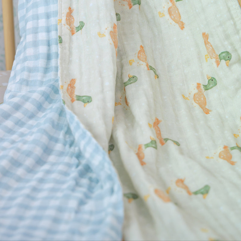 Three baby blankets with different patterns draped over a wooden chair.