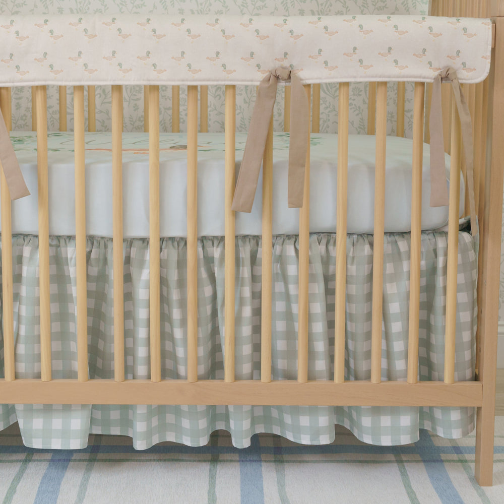 A crib bedding set with a duckling design, including a personalized blanket with the name 'William', displayed in a nursery room.