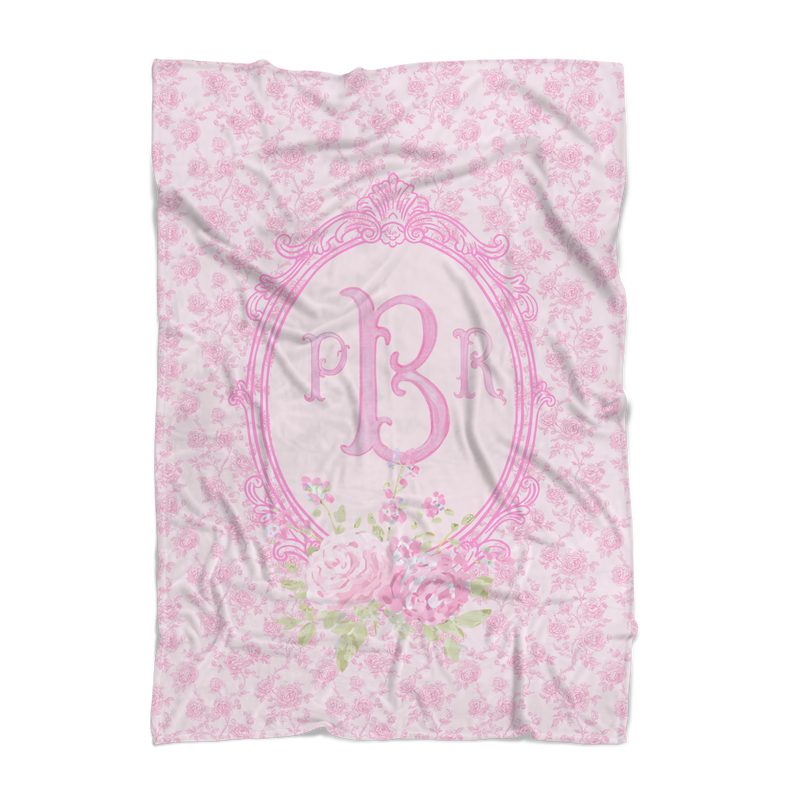 Floral patterned blanket with pink monogram on a white background