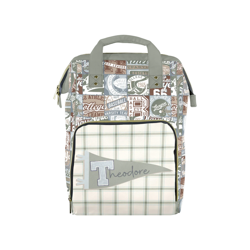A personalized diaper bag featuring a collage of vintage baseball patches on the upper body and a cream and green plaid front pocket with a gray flag patch reading 'Theodore'.