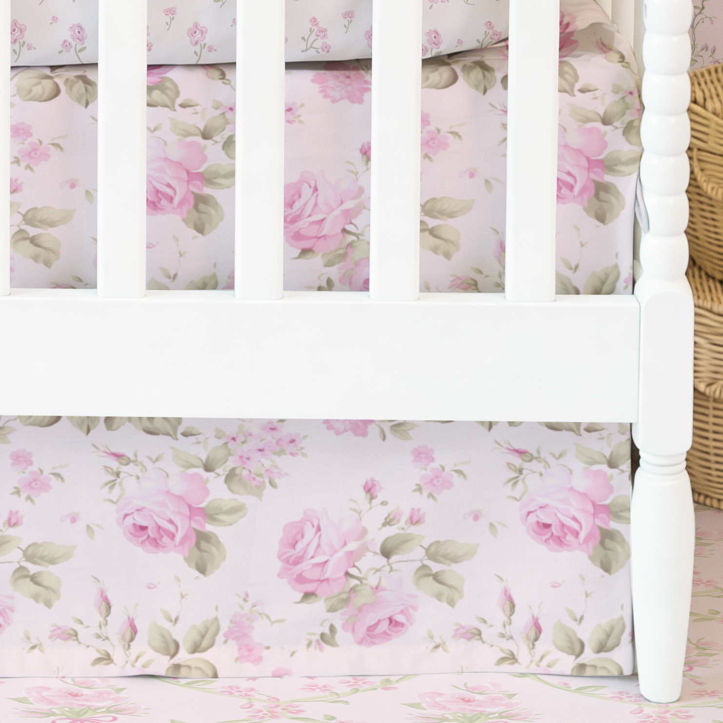 Crib with floral bedding and pink ribbons against a floral wallpapered wall.